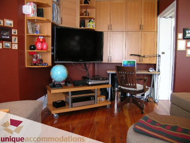 Living room with hardwood floors, a TV, and a globe on a cart. - 995 Bute Street "Rand House", Vancouver Downtown