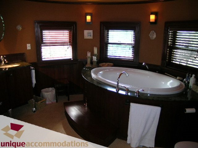 Furnished bathroom with dark wood accents, large soaking tub, and natural light from windows. - 995 Bute Street "Rand House", Vancouver Downtown