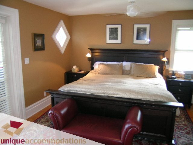 Furnished bedroom with dark wood furniture, red leather bench, and framed artwork. - 995 Bute Street "Rand House", Vancouver Downtown