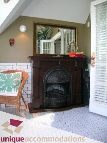 Furnished living room with a wooden fireplace, mirror, and patterned cushions. - 995 Bute Street "Rand House", Vancouver Downtown