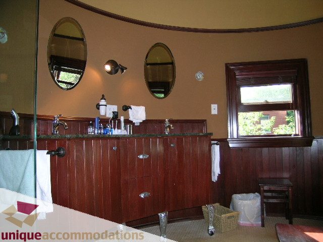 Furnished bathroom with wooden paneling and round mirrors. - 995 Bute Street "Rand House", Vancouver Downtown
