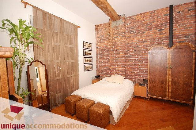 Furnished bedroom with exposed brick wall and wooden furniture. - PH1-1178 Hamilton Street, Vancouver Downtown