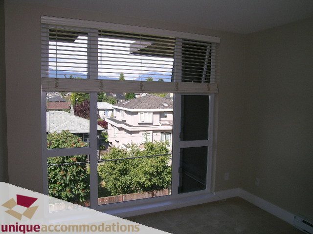 Bright living room with large window offering a city view and modern furnishings. - 405 - 3839 West 4th Avenue, Vancouver West Side