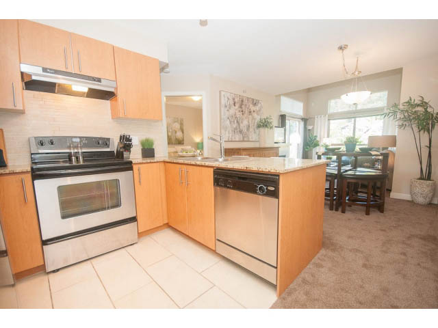 Bright kitchen with granite countertops and hardwood floors, open to a cozy living area with a city view. - 418 - 1633 Mackay Avenue, North Vancouver