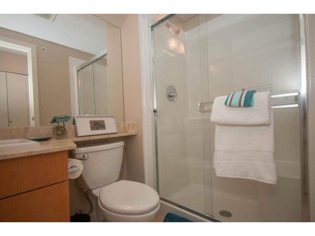 Bright bathroom with wooden cabinets and a glass shower door. - 418 - 1633 Mackay Avenue, North Vancouver