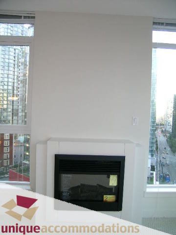 Bright living room with large window, city view, and modern fireplace. - 1101 - 1188 West Pender, Vancouver Downtown