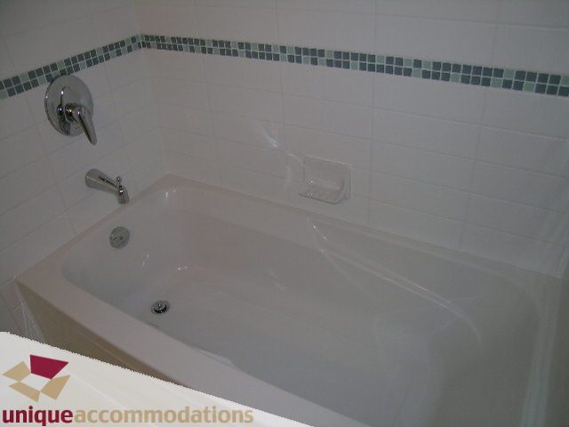 Bright bathroom with white tiles and a mosaic accent strip. - 1101 - 1188 West Pender, Vancouver Downtown