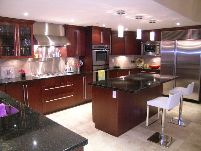 Bright kitchen with dark granite countertops, stainless steel appliances, and modern bar stools. - 202 -1280 Richards Street, Vancouver Downtown