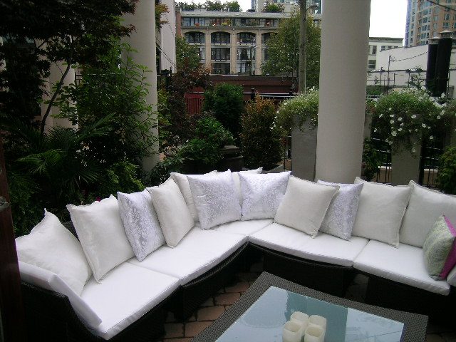 Outdoor patio with white cushioned seating and greenery, city view in background. - 202 -1280 Richards Street, Vancouver Downtown