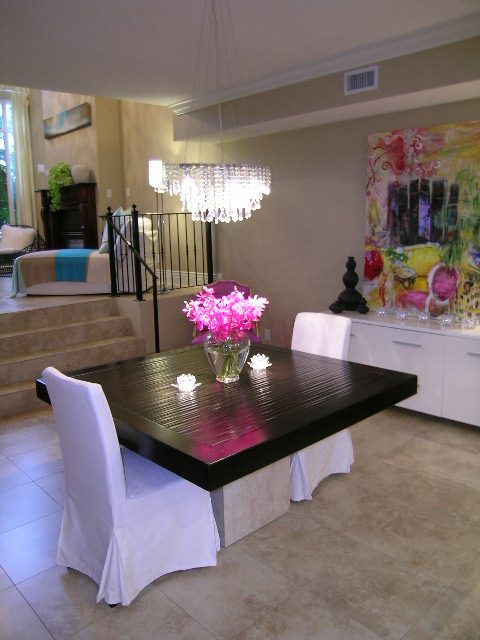 Dining area with modern chandelier, white chairs, and vibrant floral centerpiece. - 202 -1280 Richards Street, Vancouver Downtown