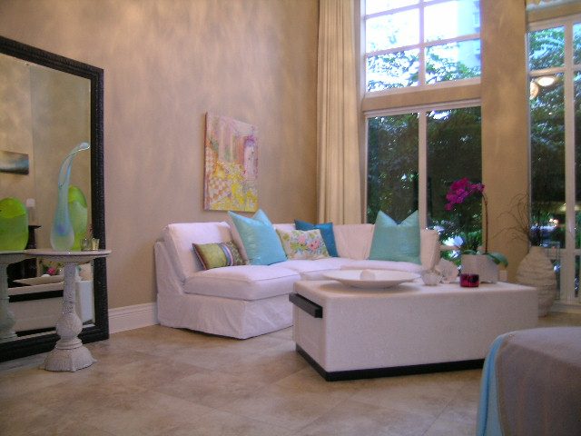 Bright living room with white couch, colorful pillows, and large windows showing greenery. - 202 -1280 Richards Street, Vancouver Downtown