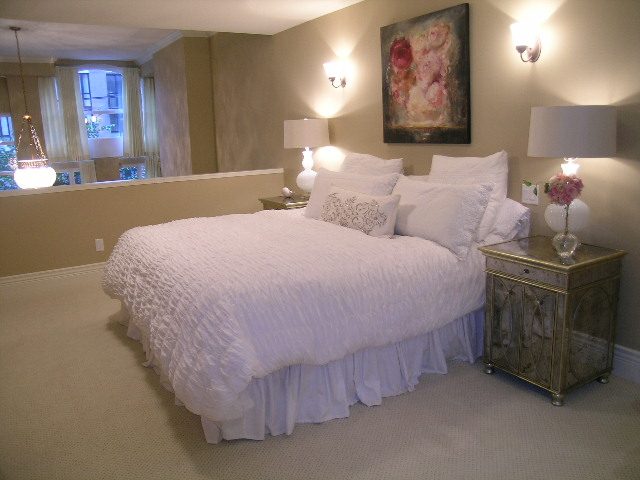 Spacious bedroom with white bedding, mirrored nightstands, and floral artwork. - 202 -1280 Richards Street, Vancouver Downtown