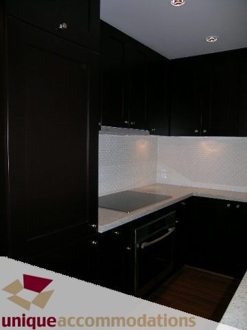 Bright kitchen with dark cabinets, white countertops, and hardwood floors. - 1802 - 821 Cambie Street, Vancouver Downtown
