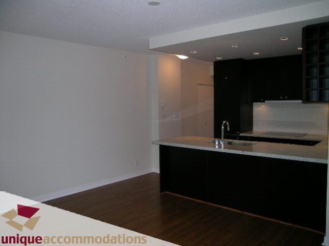 Bright kitchen with white countertops and dark cabinets, hardwood floors. - 1802 - 821 Cambie Street, Vancouver Downtown