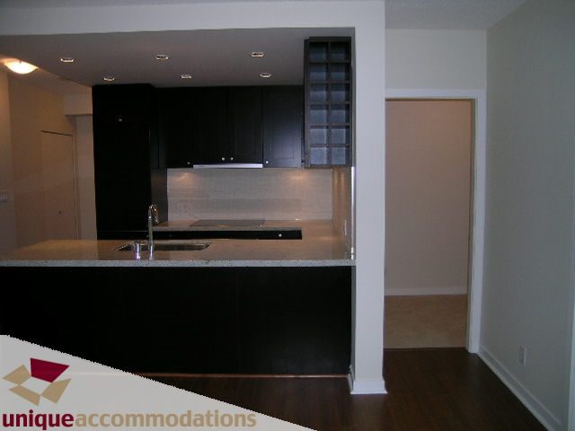 Bright kitchen with dark cabinetry and granite countertops, hardwood floors. - 1802 - 821 Cambie Street, Vancouver Downtown