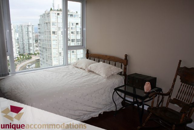 Bright bedroom with city view and wooden furniture. - 2105-1383 Marinaside Crescent, Vancouver Downtown