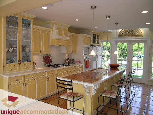 Bright kitchen with yellow cabinets, granite countertops, and a view of greenery outside. - 1849 Esquimalt Ave, West Vancouver