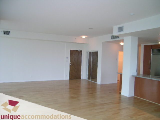 Open and airy living space with hardwood floors and a modern kitchen counter. - 2301 - 188 E Esplanade, North Vancouver