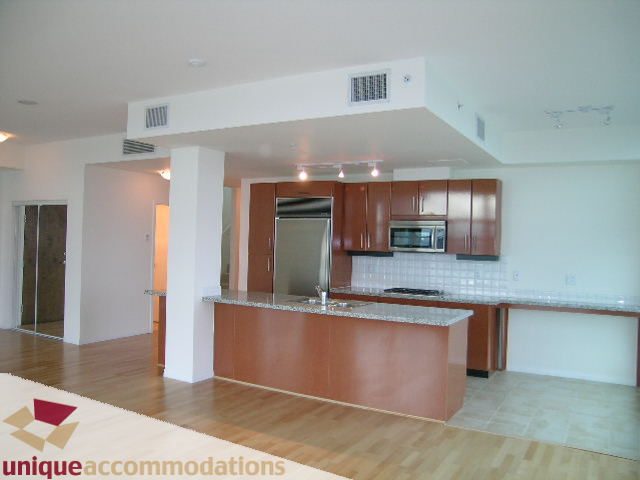 Bright kitchen with wooden cabinets, granite countertops, and hardwood floors. - 2301 - 188 E Esplanade, North Vancouver