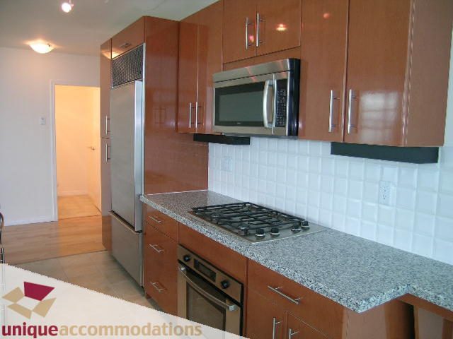 Bright kitchen with granite countertops, stainless steel appliances, and wooden cabinets. - 2301 - 188 E Esplanade, North Vancouver