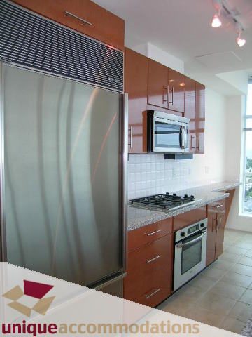 Bright kitchen with stainless steel appliances, granite countertops, and a city view. - 2301 - 188 E Esplanade, North Vancouver