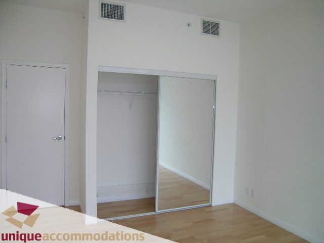 Bright bedroom with sliding mirrored closet doors and hardwood floors. - 2301 - 188 E Esplanade, North Vancouver