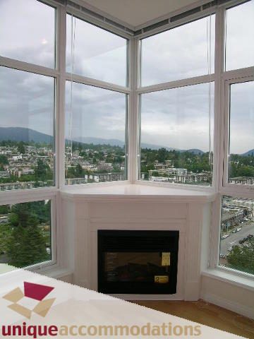 Bright living room with large bay windows, city view, and fireplace. - 2301 - 188 E Esplanade, North Vancouver