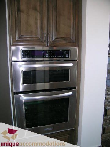 Bright kitchen with stainless steel appliances and dark wood cabinets. - 2201 - 1415 West Georgia, Vancouver Downtown