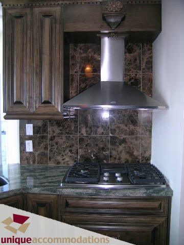 Bright kitchen with dark wood cabinets, granite countertops, and a stainless steel range hood. - 2201 - 1415 West Georgia, Vancouver Downtown