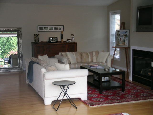 Spacious living room with hardwood floors, white couches, and a red patterned rug. - 470 Ellis Street, North Vancouver