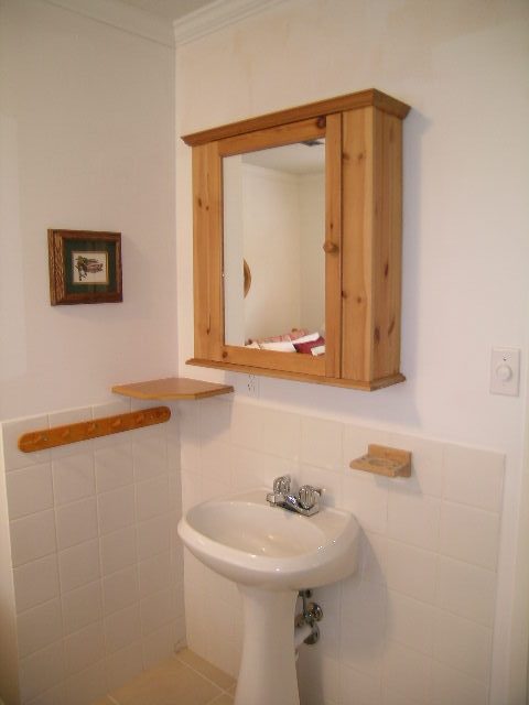 Bathroom with wooden cabinet, sink, and tiled walls. - 470 Ellis Street, North Vancouver