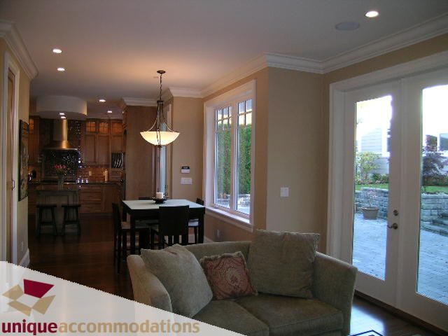 Furnished living room with hardwood floors and large windows, leading to a patio. - 1365 Kings Ave, West Vancouver