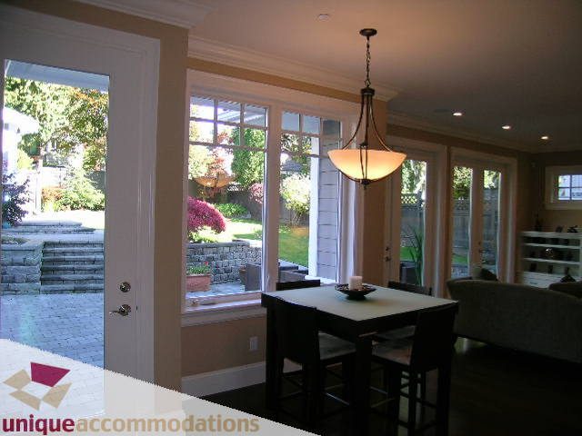 Bright dining area with hardwood floors, large windows, and a view of the garden. - 1365 Kings Ave, West Vancouver