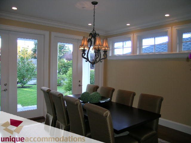 Dining room with large windows, chandelier, and view of greenery. - 1365 Kings Ave, West Vancouver