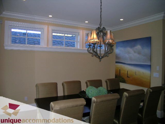 Dining room with large chandelier, wall art, and windows. - 1365 Kings Ave, West Vancouver