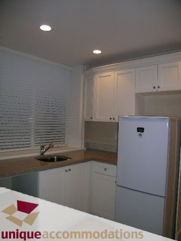 Bright kitchen with white cabinets, granite countertops, and recessed lighting. - 1365 Kings Ave, West Vancouver