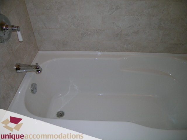 Bathroom with white bathtub and tiled walls. - 1365 Kings Ave, West Vancouver