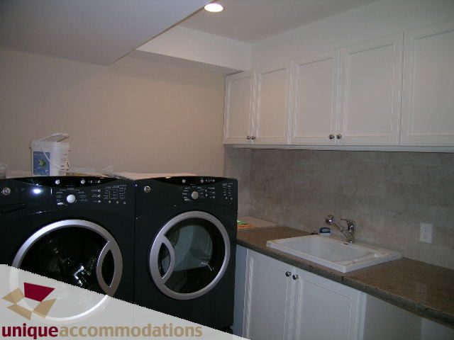 Bright laundry room with granite countertops and white cabinets. - 1365 Kings Ave, West Vancouver