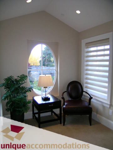 Furnished living room with arched window and white blinds. - 1365 Kings Ave, West Vancouver