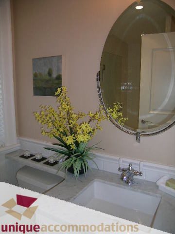 Bathroom with marble countertops, modern sink, and decorative flowers. - 1365 Kings Ave, West Vancouver