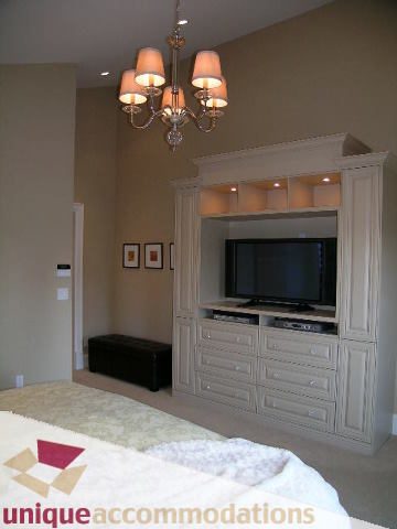 Furnished bedroom with built-in entertainment center and chandelier. - 1365 Kings Ave, West Vancouver
