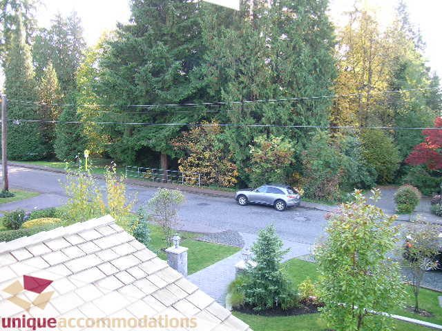 Furnished living room with hardwood floors and a view of trees and parked cars. - 1365 Kings Ave, West Vancouver