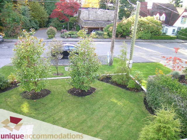 Furnished living room with cozy seating and large windows, offering a serene garden view. - 1365 Kings Ave, West Vancouver