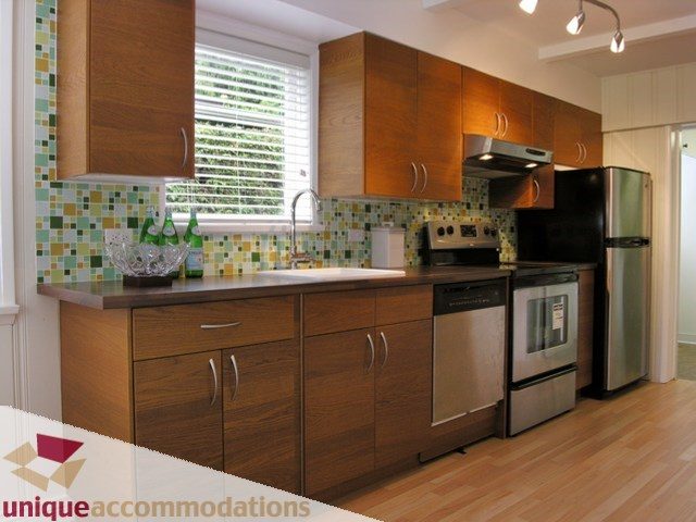Bright kitchen with wooden cabinets, stainless steel appliances, and hardwood floors. - 1132 West 24th Street, North Vancouver