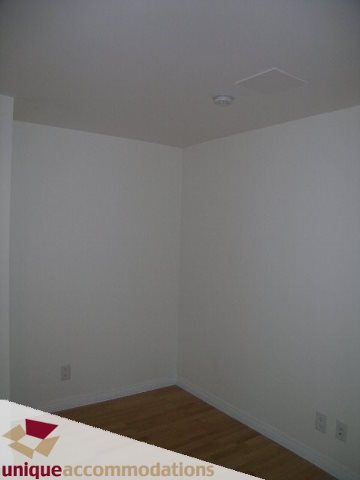 Empty bedroom with hardwood floors and white walls. - TH9 - 188 East Esplanade, North Vancouver
