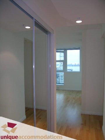 Bright living room with hardwood floors and sliding glass doors leading to a balcony, showcasing a city view.
