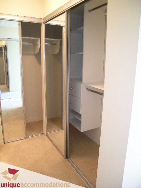 Bright walk-in closet with mirrored sliding doors and built-in shelves. - 905 - 683 Victoria Park West, North Vancouver