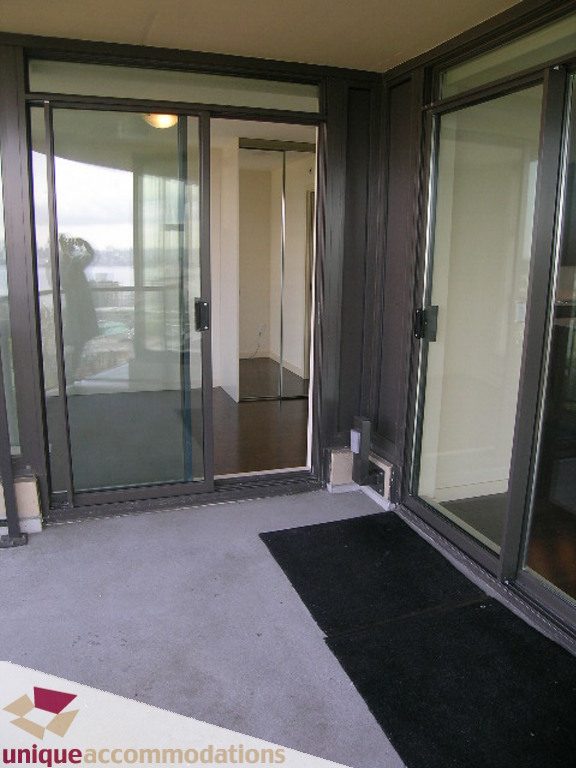 Furnished living room with sliding glass doors leading to a balcony, city view. - 905 - 683 Victoria Park West, North Vancouver