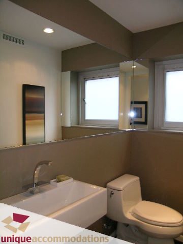 Modern bathroom with dual sinks, large mirror, and neutral tones. - 4070 West 18th Avenue, Vancouver West Side