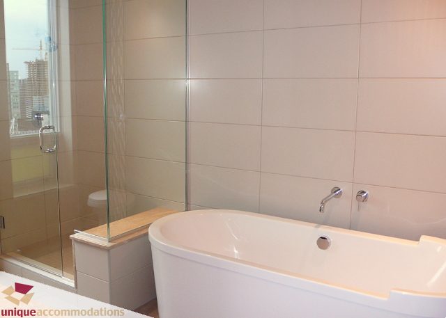 Spacious bathroom with modern fixtures and large windows offering a city view. - 2802 - 1277 Melville Street, Vancouver Downtown